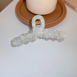 Gros plan d'une pince à cheveux en résine blanc nacré avec texture coquillage