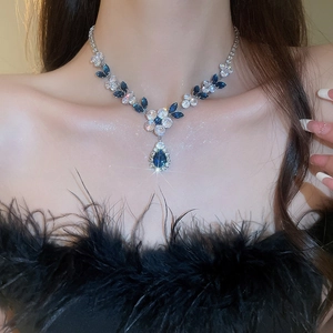Detail of silver-tone floral necklace featuring blue and clear zircon on female model