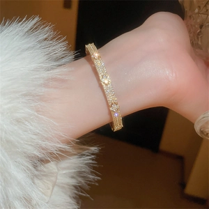 Macro detail of gold-plated clover bracelet with sparkling cubic zirconia on a wrist