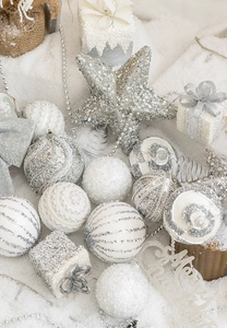 Detailed view of silver and white Christmas tree ornaments with glitter on snow
