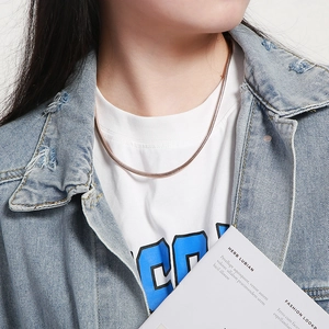 Close-up of elegant rose gold square snake chain necklace on female model neck