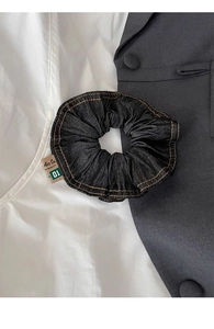 Detail of dark blue denim scrunchie with orange stitching and vintage fabric label