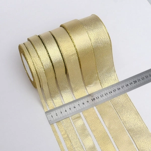 Golden glitter ribbon in various widths with steel ruler for size comparison