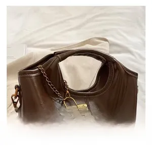 Detail of vintage oil wax leather tote with circular hollow handle and golden chain accent