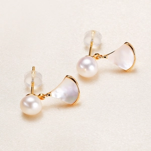 Elegant fan shaped gold pearl earrings with freshwater pearls on silk texture background