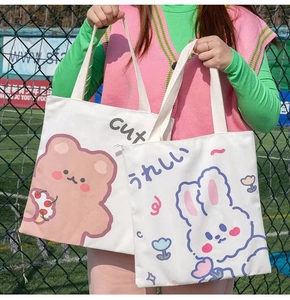 Detail view of white canvas tote bags with cute bear and rabbit prints for students