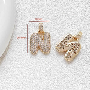 Detailed view of gold letter N pendant with white zircon pavé and 29.9mm size markings