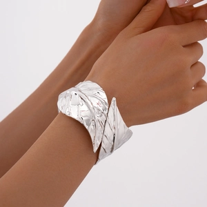 Detailed view of silver wide leaf cuff bracelet with textured metallic finish on wrist