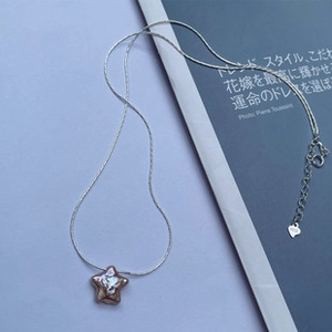Dettaglio ravvicinato di una collana con ciondolo a stella in argento S925 su rivista