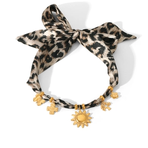 Detail of leopard print ribbon choker with gold cross, sun and butterfly charms