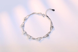Detail of silver double-layered snake chain bracelet with six dainty star charms