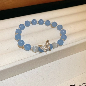 Détail du bracelet en perles d'agate bleue avec breloque papillon sertie de diamants