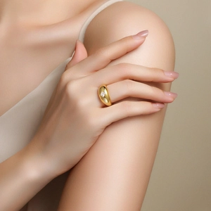 Detail of a wide gold-plated ring featuring a princess-cut square moissanite on a model