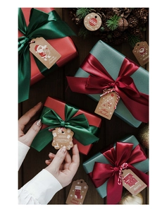 Close-up of Merry Christmas kraft paper gift tags with festive patterns and red ribbons