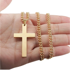 Detailed view of a hand holding a polished gold cross pendant with a Cuban chain