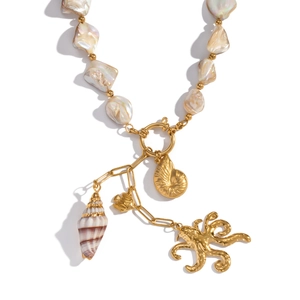 Macro detail of octopus and seashell charms on a baroque pearl and gold beaded necklace