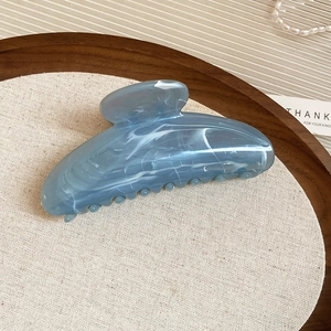 Gros plan de la pince à cheveux en acrylique marbré bleu sur un plateau en bois