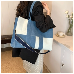 Detail view of large canvas denim tote bag with adjustable shoulder strap on a model
