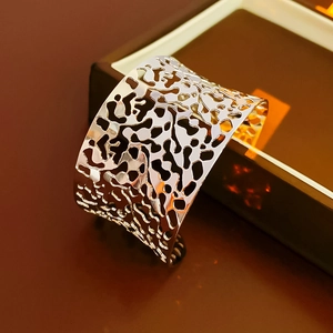 Macro detail of silver wide cuff bracelet featuring irregular organic cut-outs and polished finish