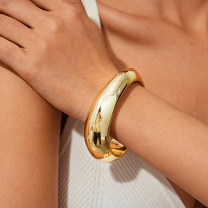 Close-up of chunky gold geometric metal bracelet worn by model for high-end fashion styling