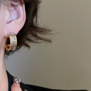 Detailed close-up of 18k gold plated C-shaped earrings with dual-tone textured finish