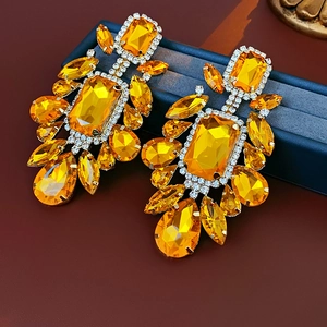 Detail shot of luxurious gold-toned earrings with amber faceted crystals and tiny diamonds