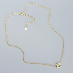 Detail of gold evil eye necklace showing green gemstone center and micro-pave diamonds
