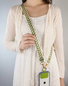 Close-up of adjustable white wide fabric phone strap with green leaf embroidery pattern