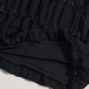 Close-up of black pleated fabric texture with delicate lace trim and smooth lining detail