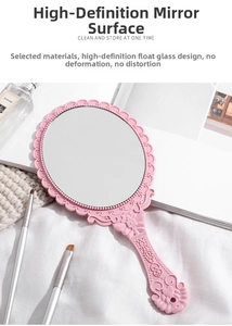 Detail of pink vintage hand-held mirror with embossed floral patterns on a vanity
