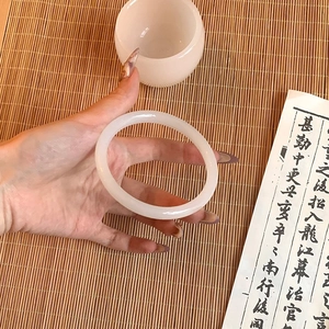 Detail of a translucent white glass bracelet held in a classic Chinese cultural setting