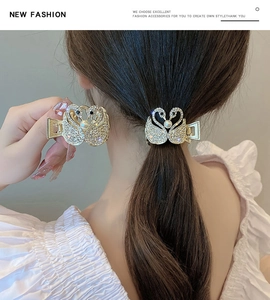 Détail d'une pince à cheveux cygne dorée avec strass scintillants et une perle