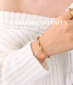 Detail of 18K gold-plated titanium steel chain bracelet on a wrist with white sweater