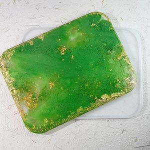 Primer plano detallado de una bandeja de resina epoxi verde con láminas de oro y purpurina