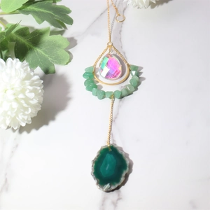 Macro detail of agate slice and pink prism crystal on a golden suncatcher hanging