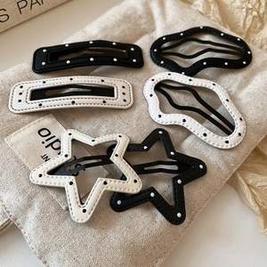 Detailed view of black and white polka dot hair clips with fine stitching on canvas