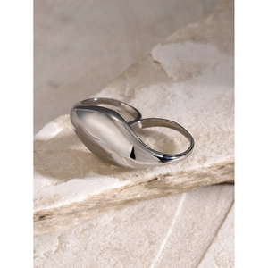 Macro detail of polished stainless steel double-finger ring on a textured rock surface