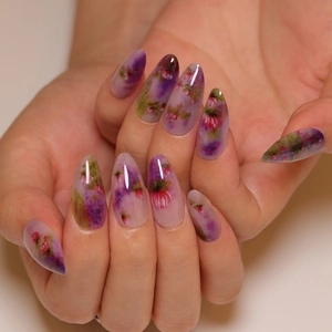 Faux ongles amande fleurs à l'aquarelle avec pétales violets et décor de feuilles