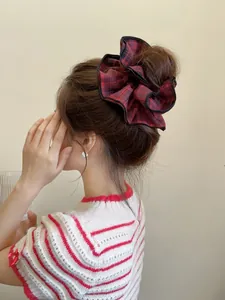 Macro view of a large plaid scrunchie with red and black checkers on a high bun hairstyle