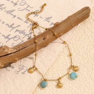 18K gold plated anklet with shell charms and turquoise beads on a rustic wood branch