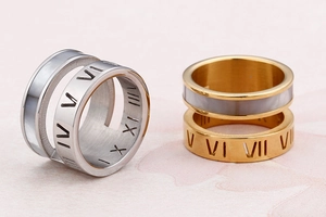 Macro view of gold and silver Roman numeral rings with white shell inlay on pink texture
