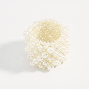 Macro detail of multi-layer elastic pearl bracelet featuring glossy white beads on white background