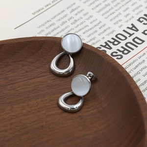 Modern cat's eye stone earrings with silver geometric design on a dark wood tray