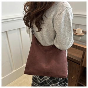 Detail view of large dark brown suede tote bag showing soft texture and draping on shoulder