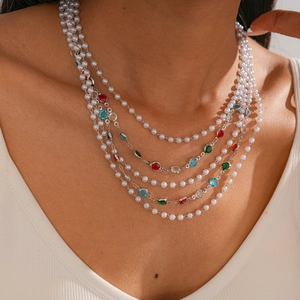 Close-up of multi-layer baroque pearl necklace with colorful gemstones on a female model
