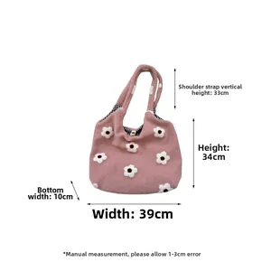 Detailed view of pink knitted tote bag showing white flower embroidery and plaid lining