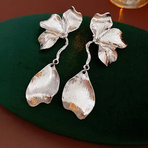 Silver brushed metal flower and leaf earrings on dark velvet background display