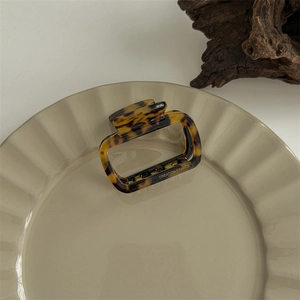 Close-up of tortoise shell square hair claw clip with Creation France logo on ceramic plate