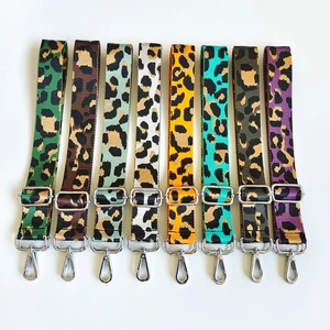 Detail of adjustable nylon leopard print bag straps with silver metal hooks and buckles