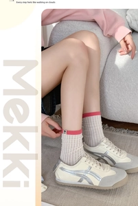 Close-up of cream ribbed cotton crew socks with pink trim and small tag on a model